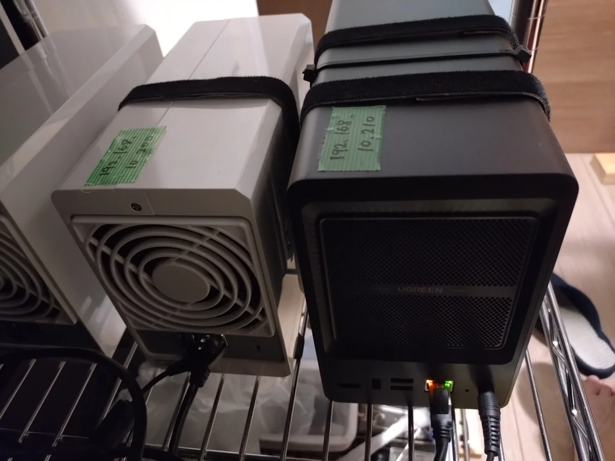 運営者が24時間稼働させている無印UGREEN NASync DXP2800（右・黒）の背面。2.5GbEのLANポートが1つだけ搭載され、LAN緑LEDが点灯している
