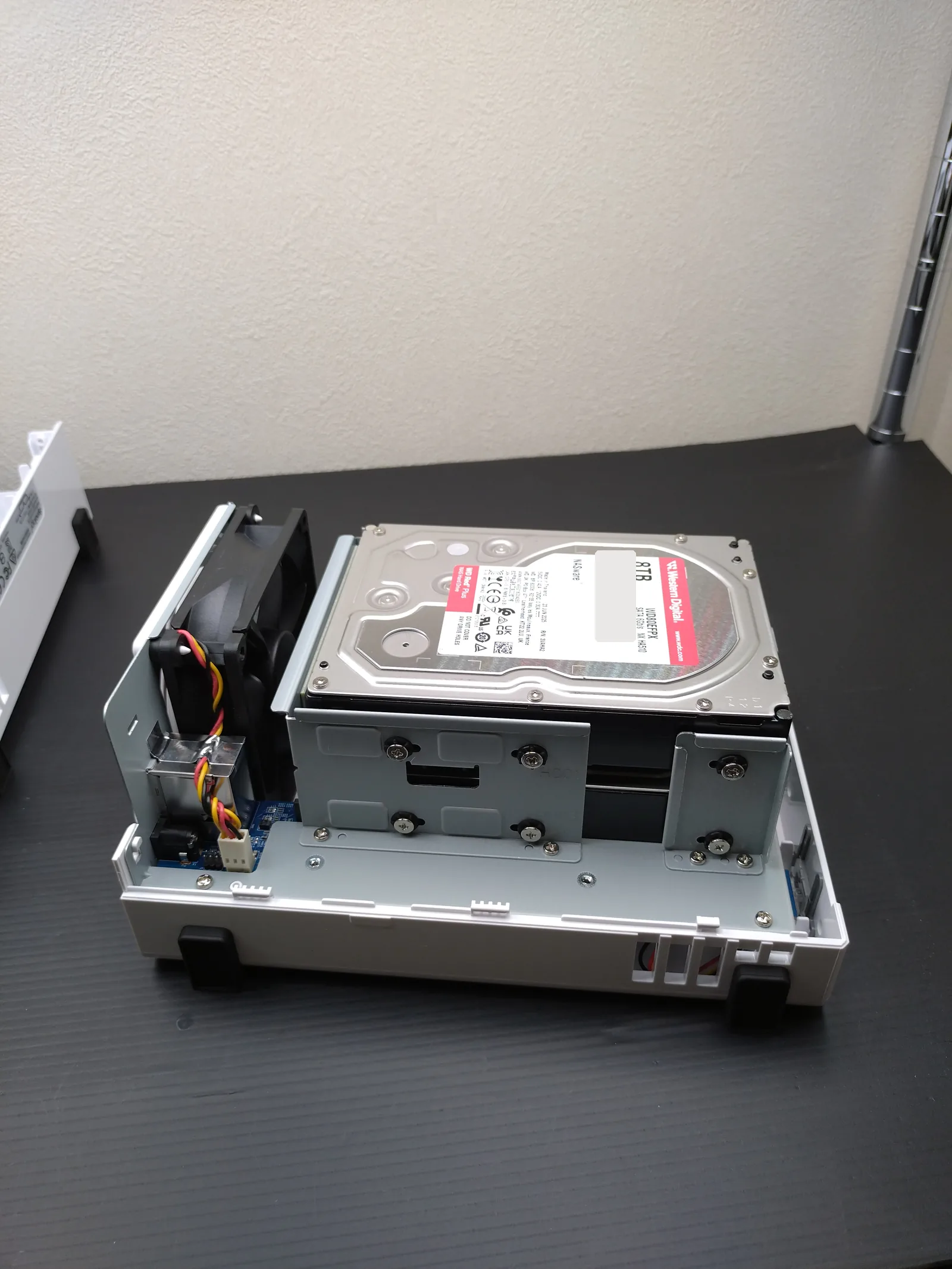 Synology DS223JのHDDを側面のネジで固定した状態。奥に背面の冷却ファンが見える